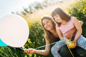 Girl with Special Needs Sister Holding Balloon and Smiling