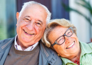 Older Couple Smiling Outdoors and Leaning on Each Other